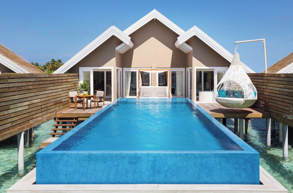 An overwater bungalow with a pool and hanging lounge chair.