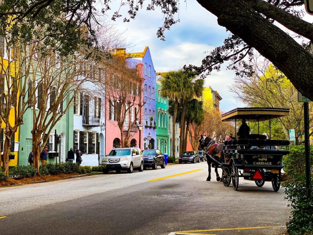 Charleston street lined with colorful buildings and a horse drawn carriage.