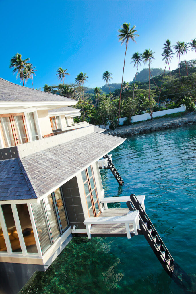 Koro Sun Resort and Rainforest Spa Bungalow with palm trees and mountains in the background.