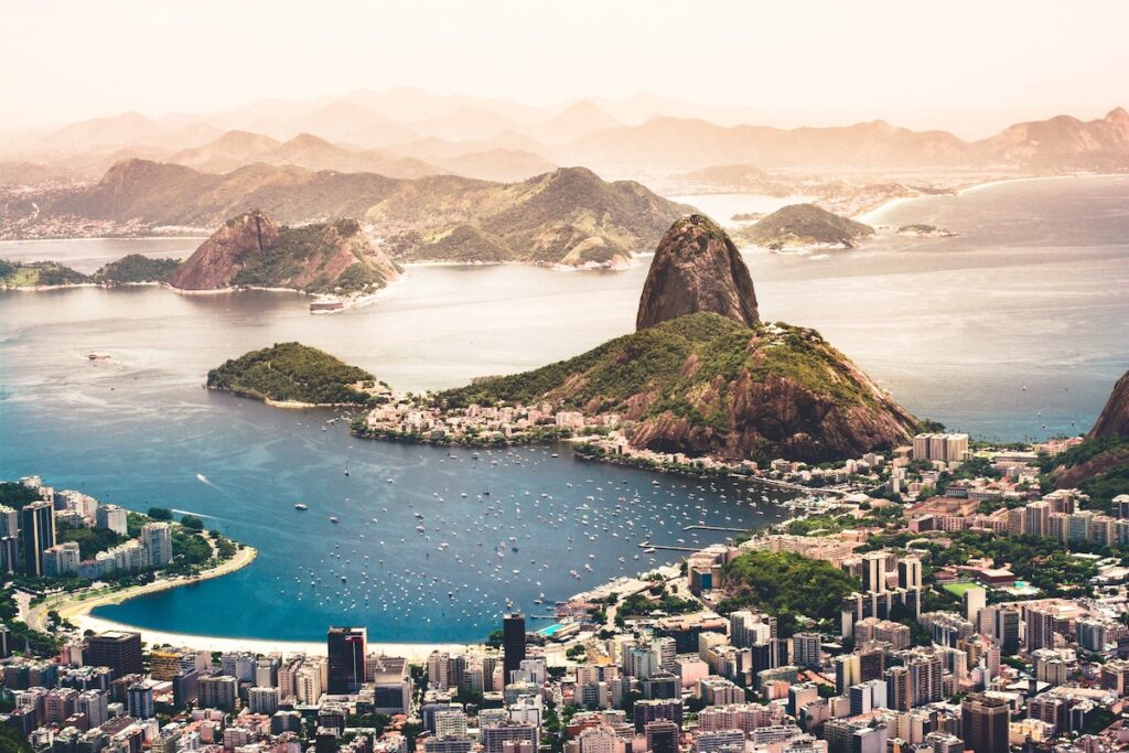Rio de Janeiro coastline with buildings, boats, and large mountains in the distance.