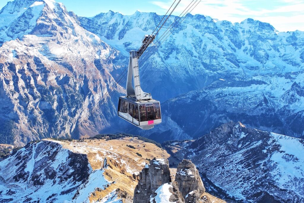 A cable car surrounded by snow capped mountains in Switzerland.