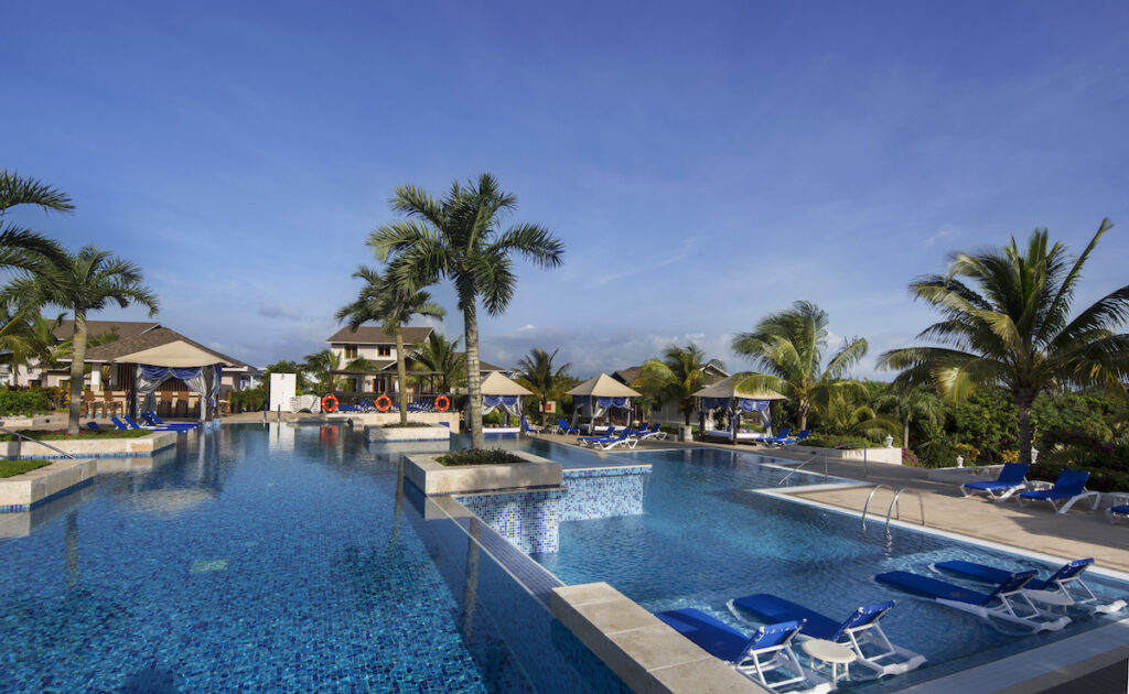 A pool at the Royalton Cayo Santa Maria in Cuba with blue lounge chairs and palm trees.